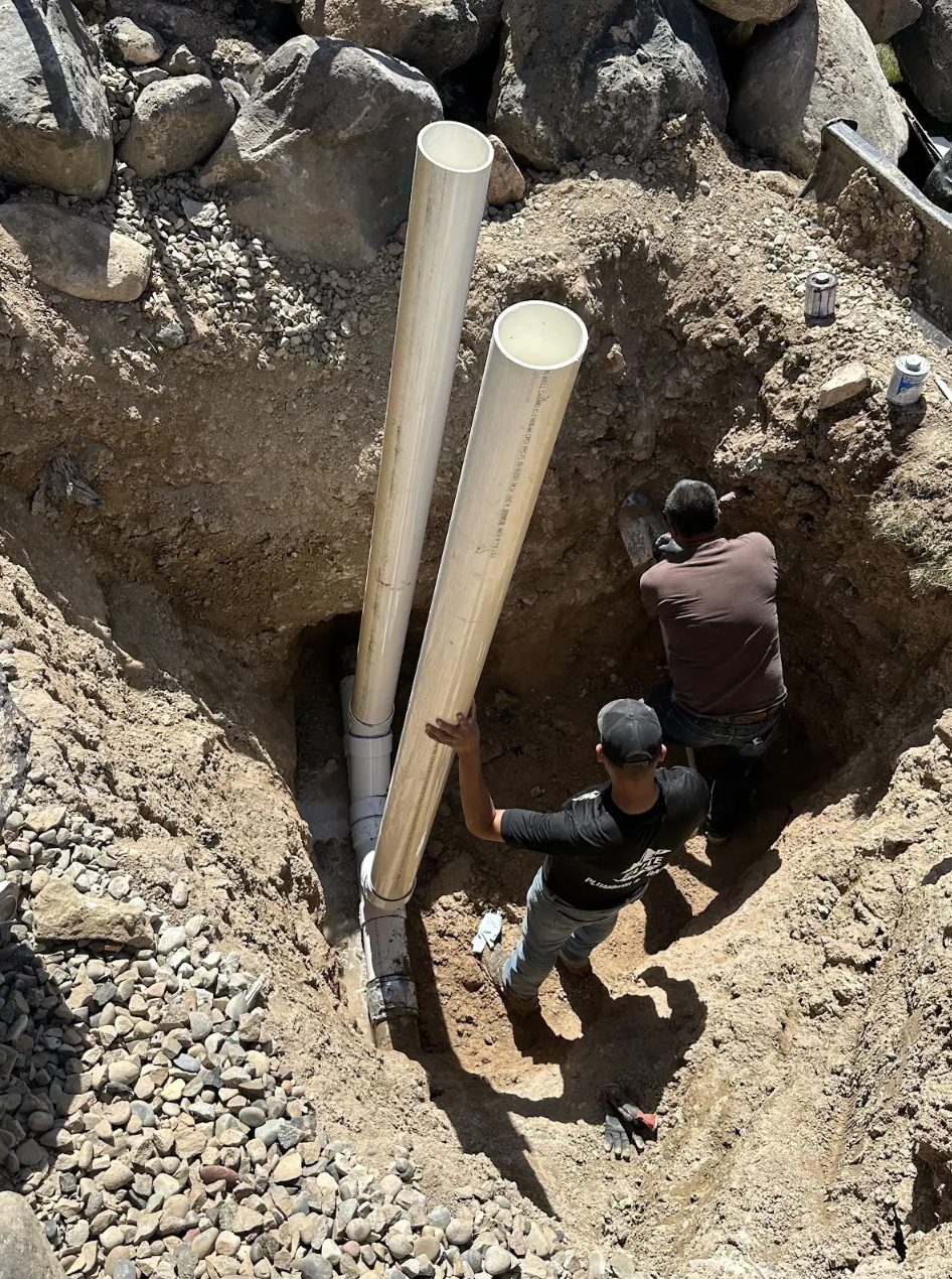 Elite Plumbing & Drains crew setting sewer line pipe in a Grand Valley trench